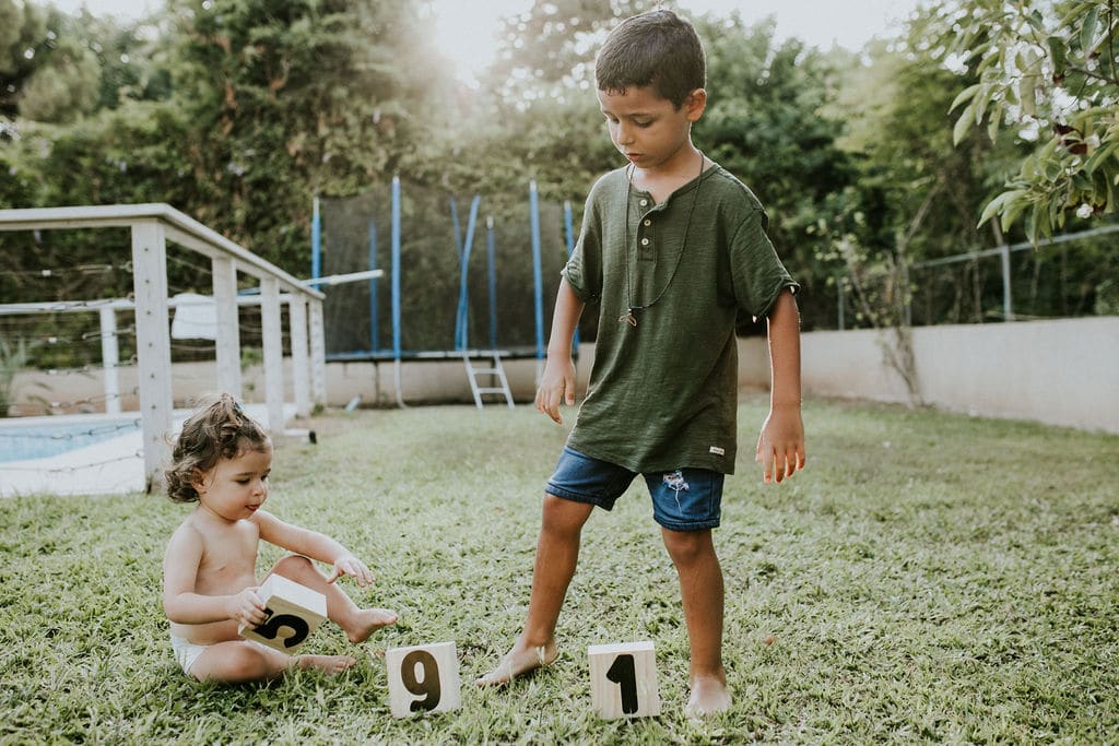 יהונתן ומאיה משחקים על הדשא בקוביות עץ